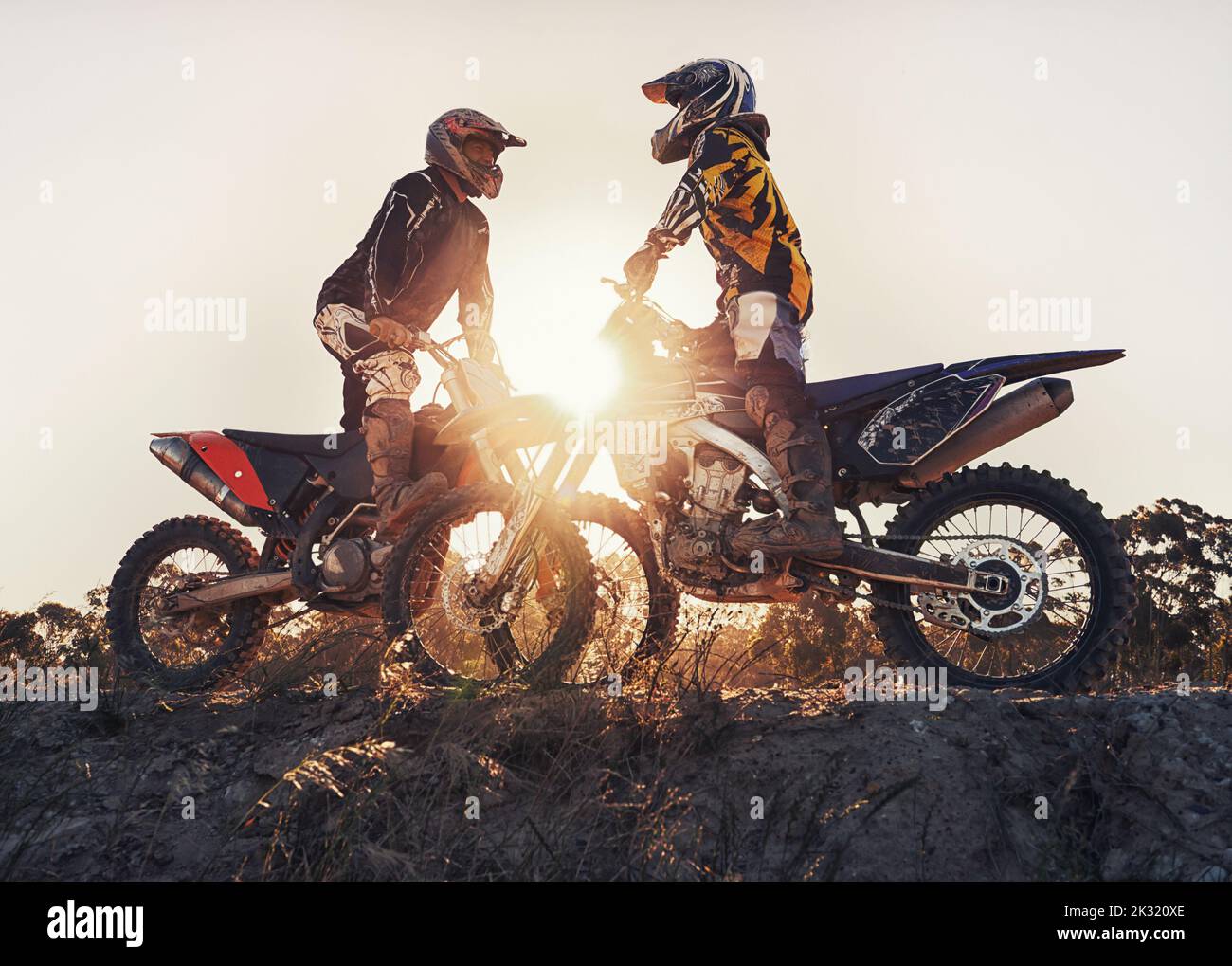 That was an awesome day on the track. two motocross riders out on the track against the setting sun. Stock Photo
