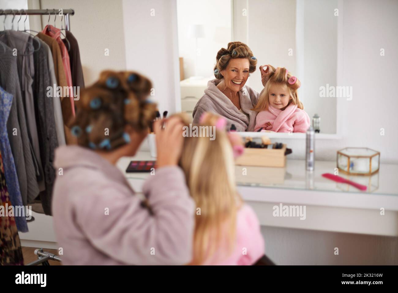 Giving her some curls. a young mother getting her daughter ready for an important event. Stock Photo