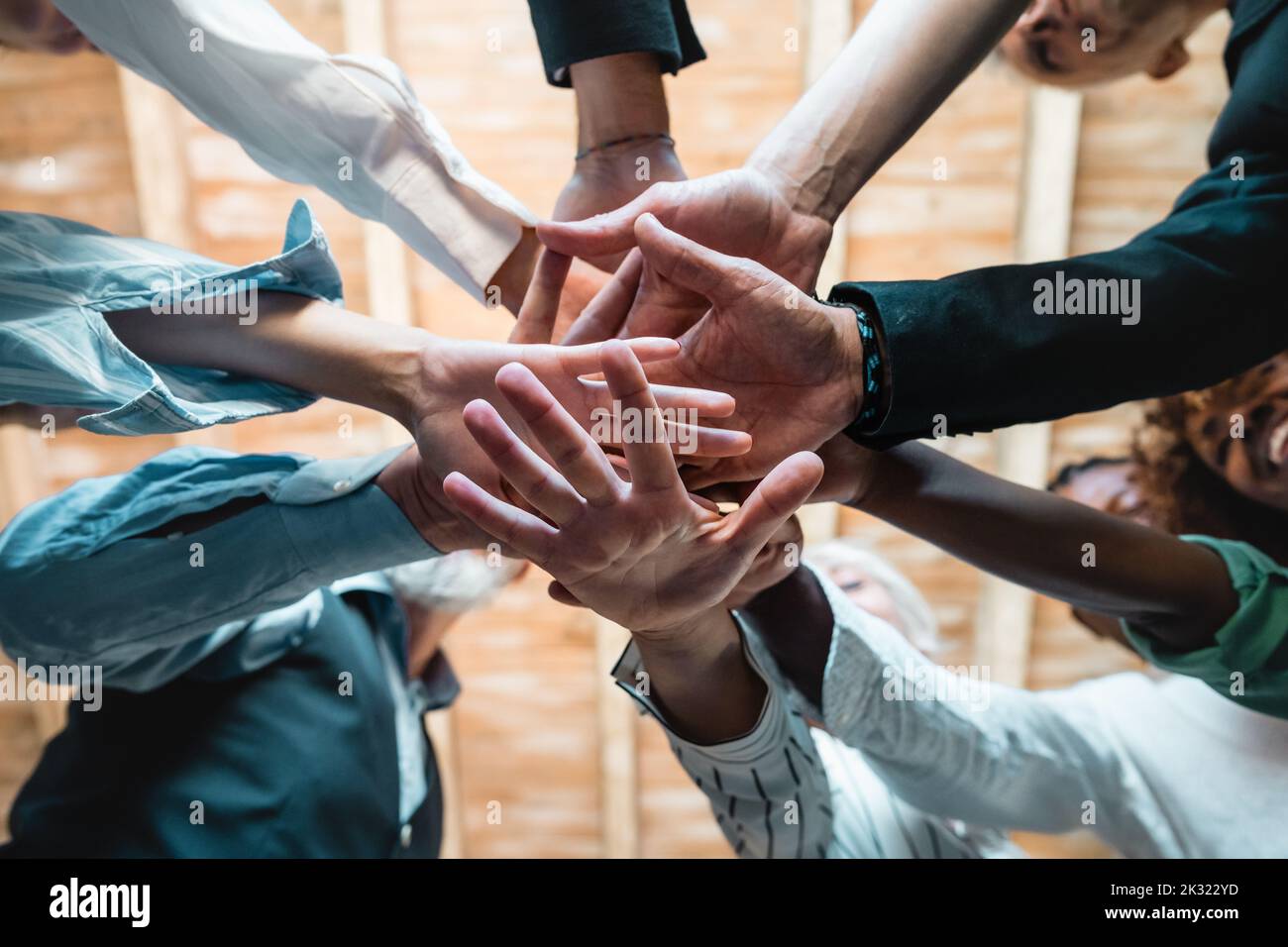 Group of businesspeople joining hands together standing in circle, closeup view from bottom - Creative business teamwork building concept - soft skill Stock Photo