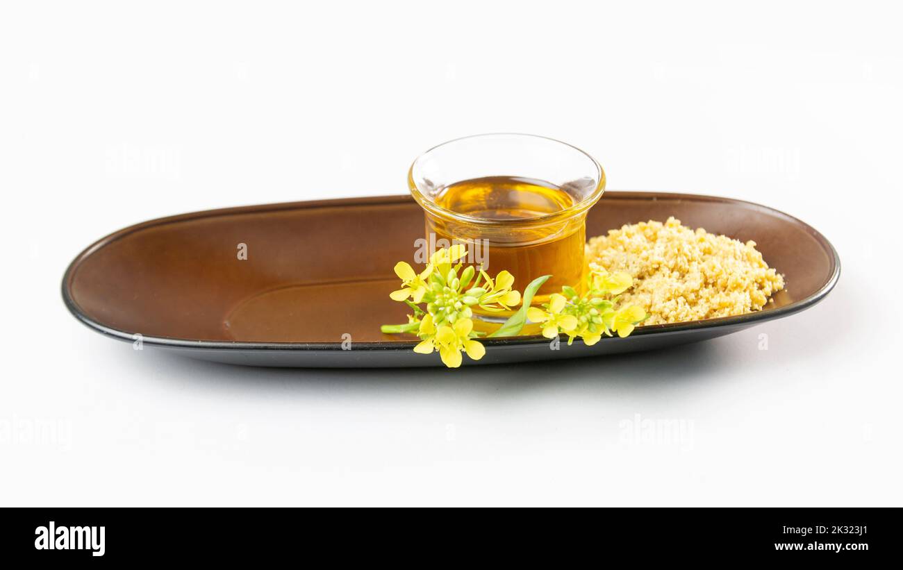 mustard oil, seed paste and flower on dish white blank space. useful in cooking and external body care. Mustard seeds and oil with mustard plants with Stock Photo