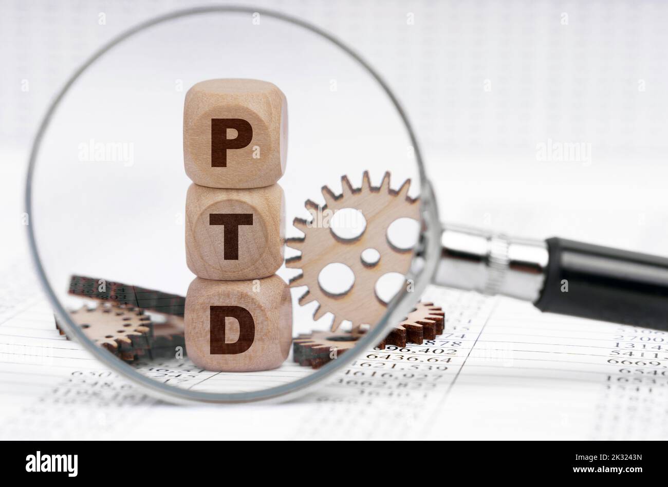 Business concept. There is a magnifying glass on the documents that points to the cubes with the inscription - PTD Stock Photo