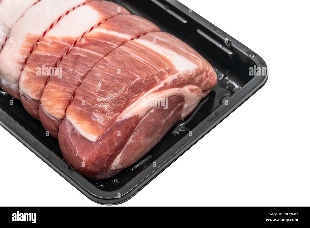 Close up a raw cut of pork loin, tied up and rolled with butcher's string in a black plastic container, 45-degree angle view, detailed tissue of fresh Stock Photo