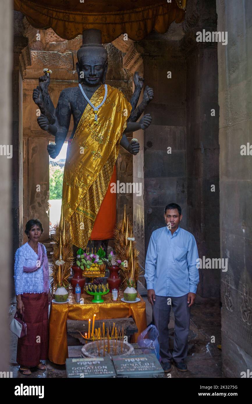 Two worshippers stand each side of a statue of Vishnu, or Ta Reach, in the Western Gopura (West Gate) entrance to Angkor Wat, Siem Reap, Cambodia Stock Photo