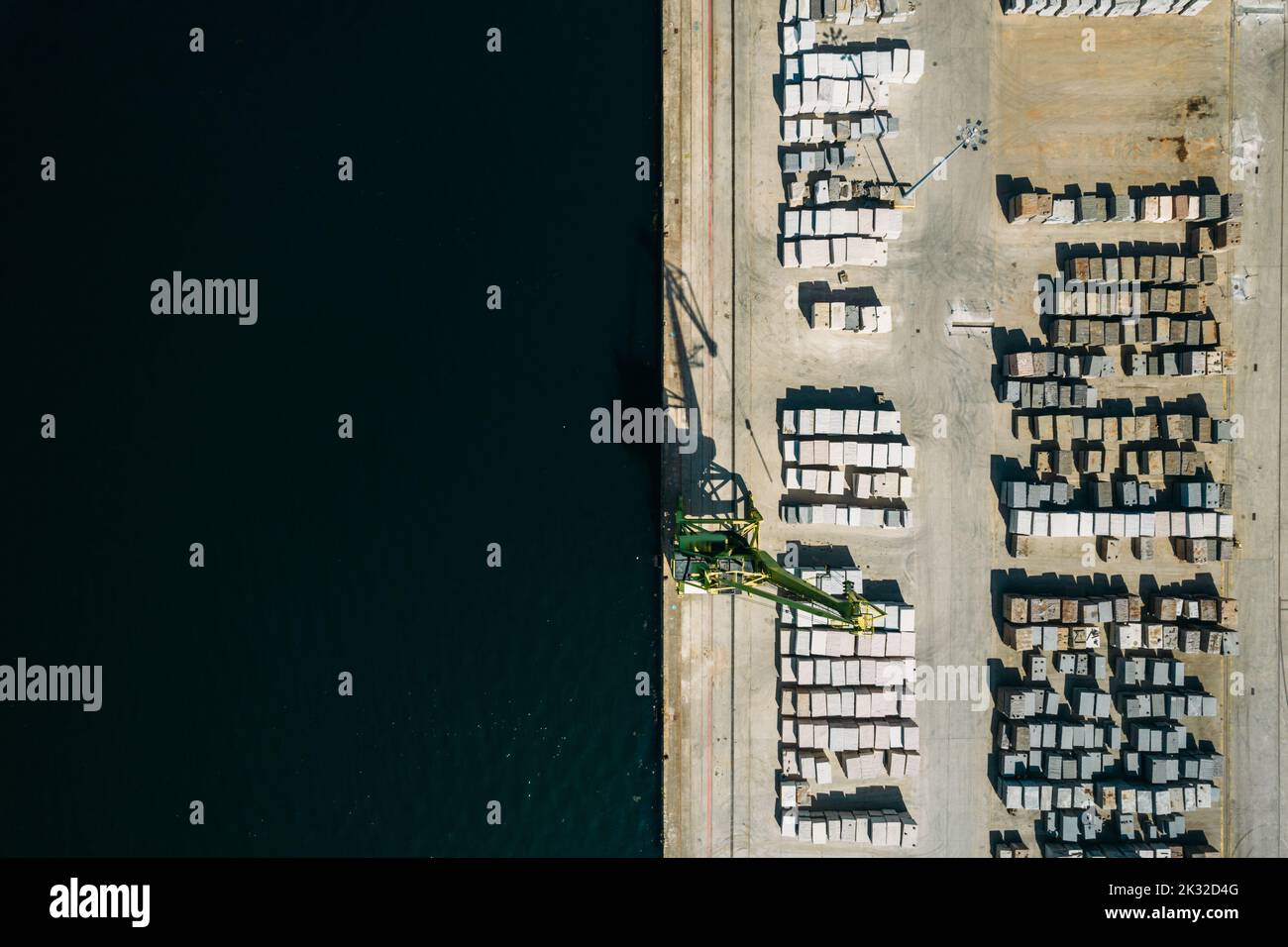 Aerial drone top down view of containers and concrete blocks spread across a busy port, logistic and international trade concept Stock Photo