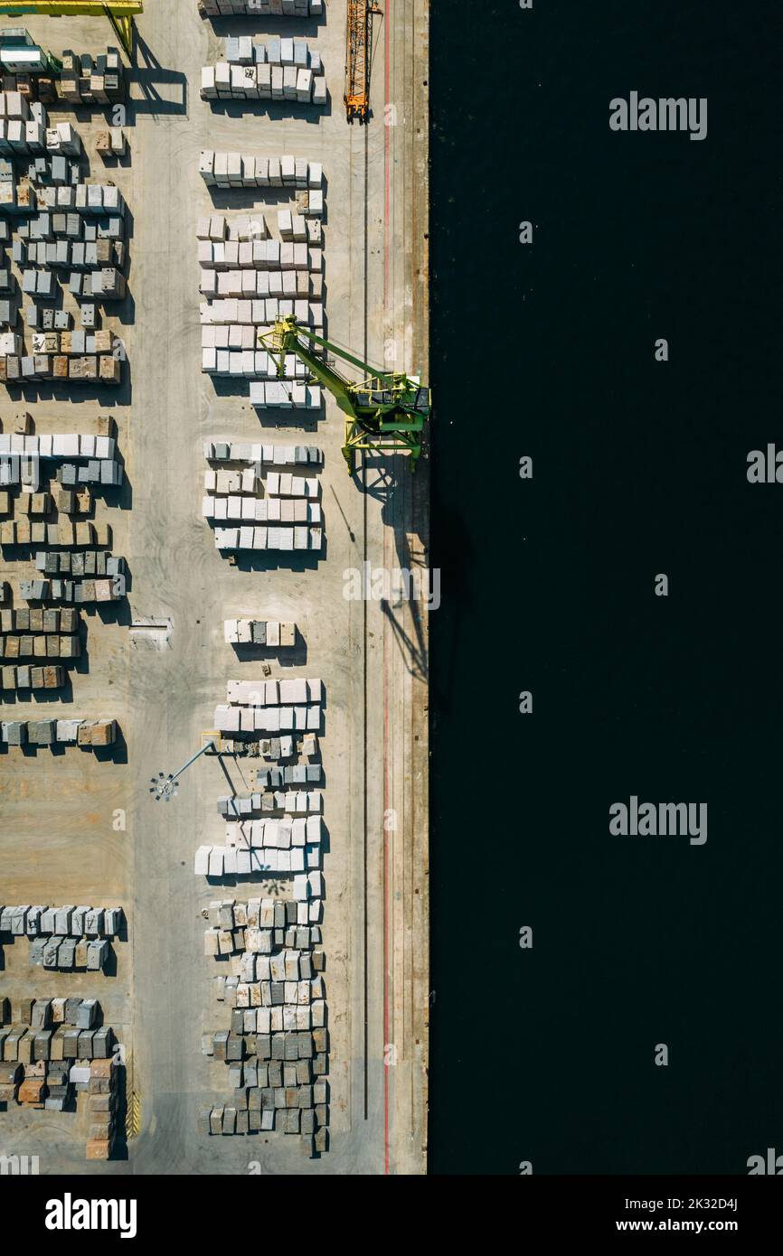 Aerial drone top down view of containers and concrete blocks spread across a busy port, logistic and international trade concept Stock Photo