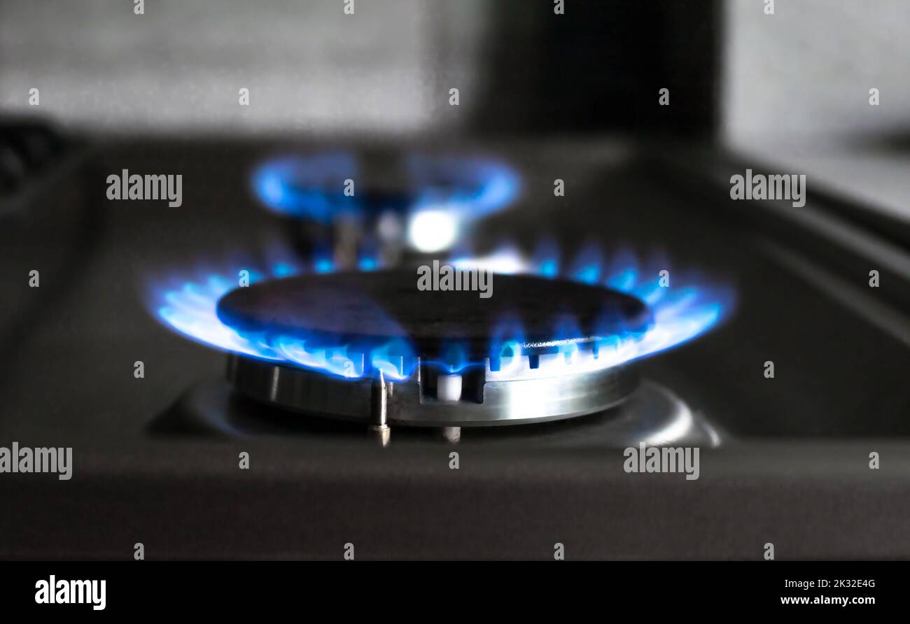 Close-up of a blue fire from a kitchen stove. two gas burners with a burning flame. economy concept Stock Photo