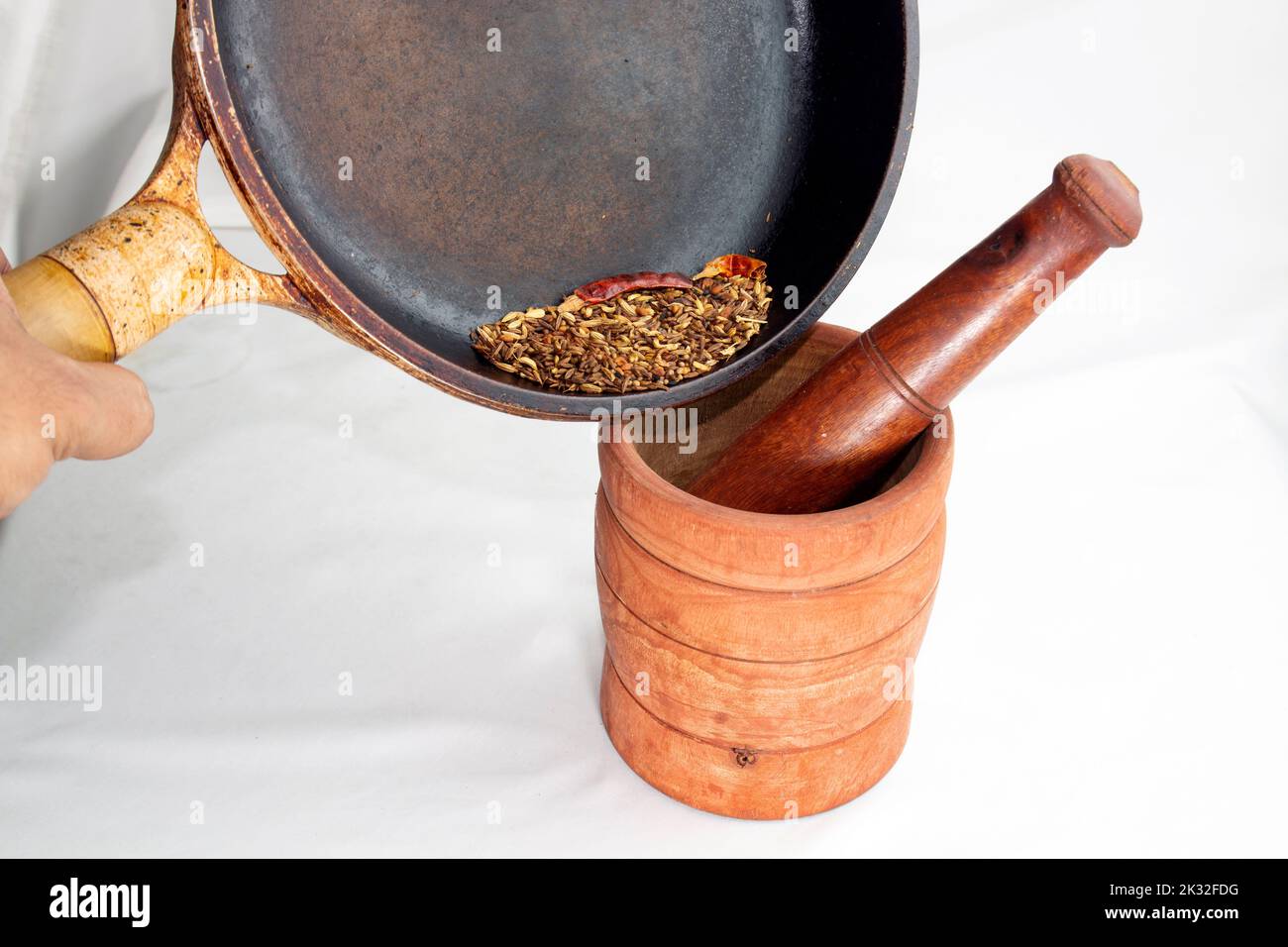 heated five spices pouring into wooden grinder to crash it for cooking. Asian traditional handmade spice powder for adding best flavour to cooking. Stock Photo
