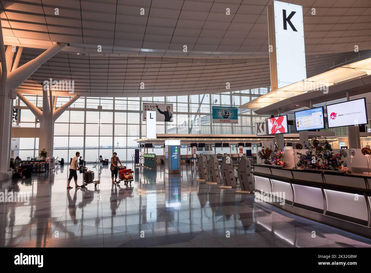 Travelers push trolleys of luggage at Haneda International Airport