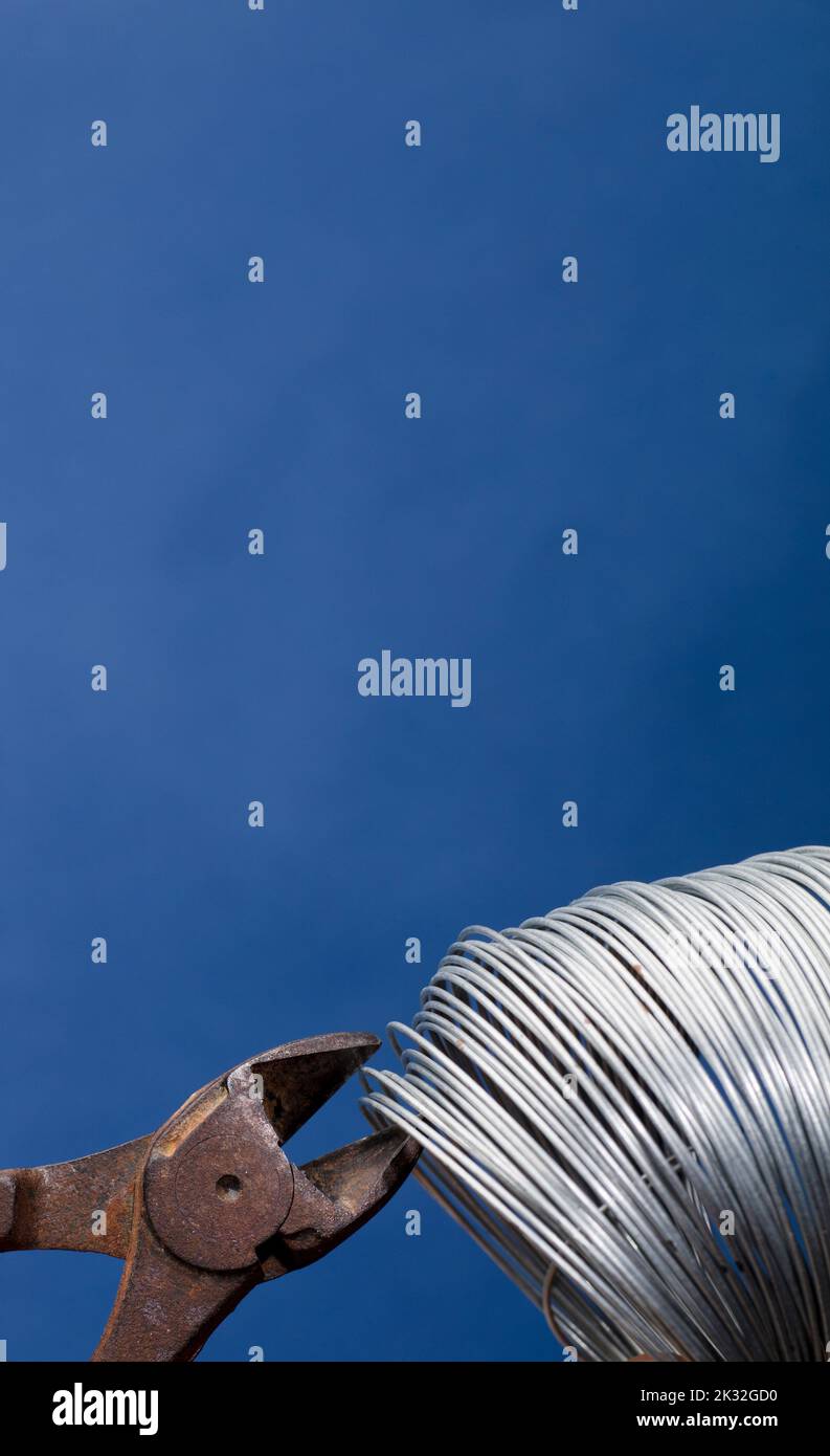 coiled metal wire cutting pliers, blue background Stock Photo