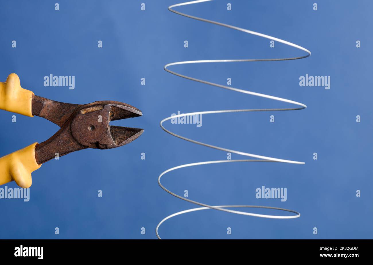 coiled metal wire cutting pliers, blue background Stock Photo