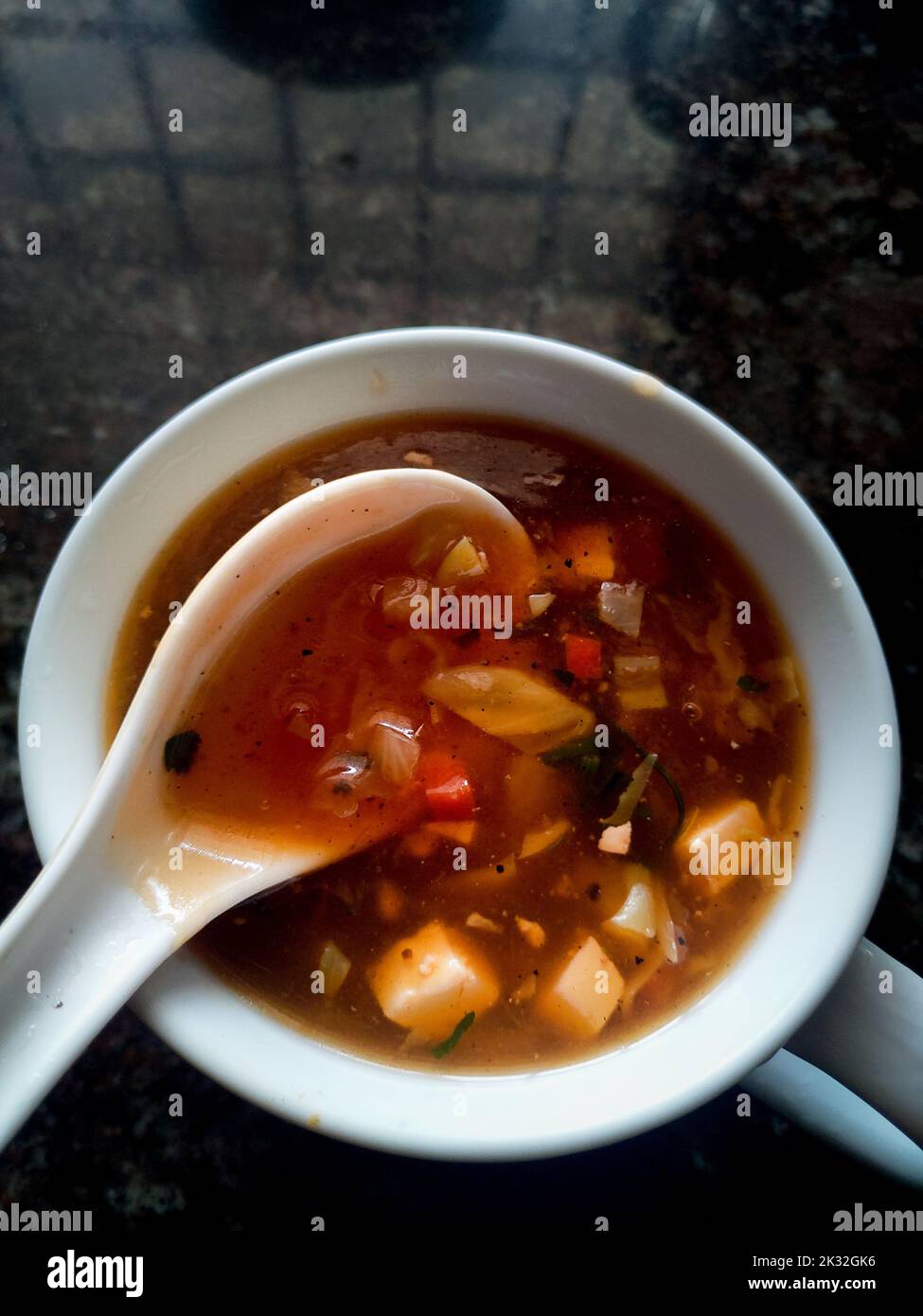 Home made Hot and sour mix vegetable soup in a white bowl with a spoon. Uttarakhand India. Stock Photo