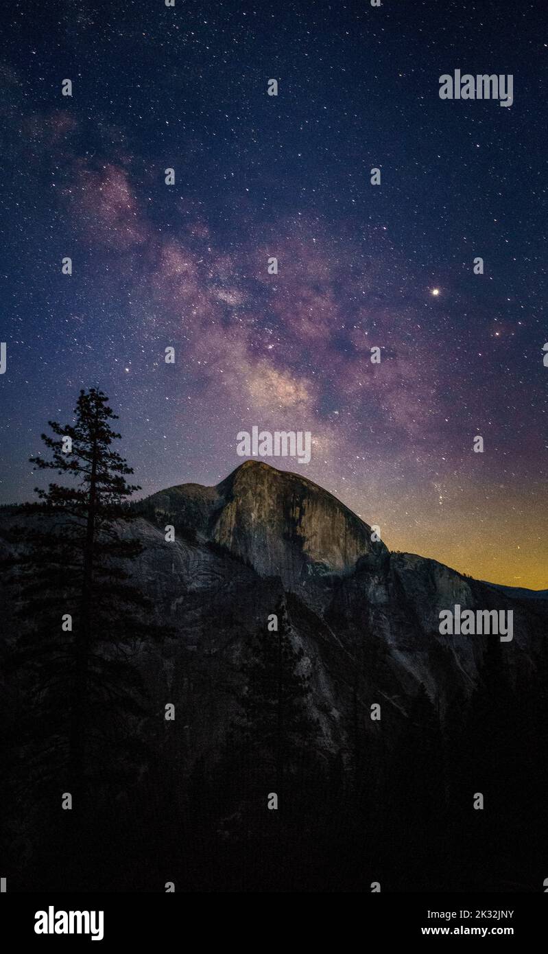 A vertical shot of a mesmerizing starry night sky over the rocky ...