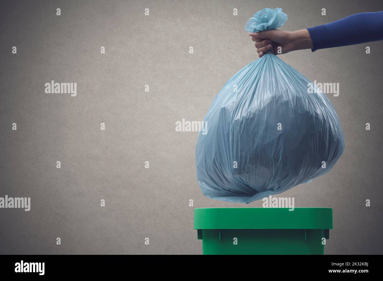 Woman putting a huge garbage bag in a trash bin, undifferentiated waste