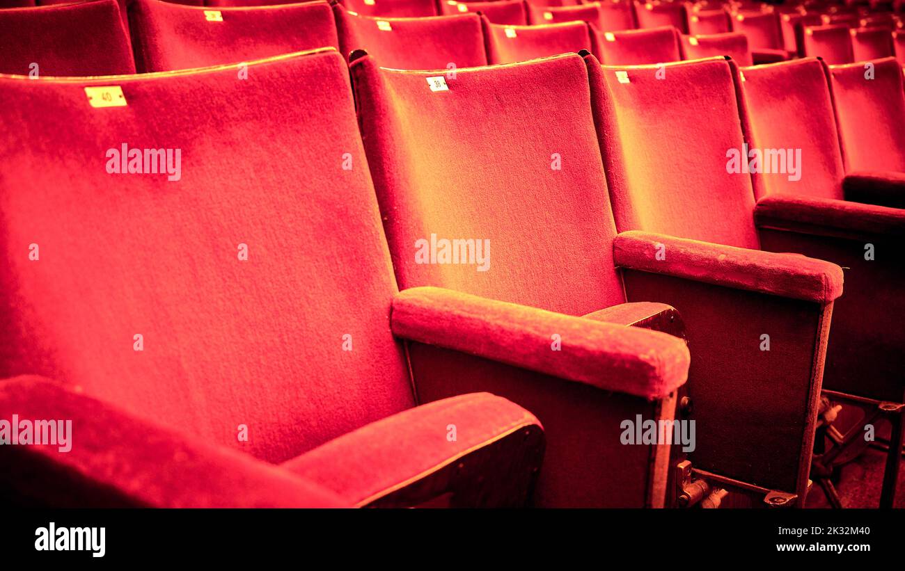Tired and well used rows  of red theatre seats Stock Photo