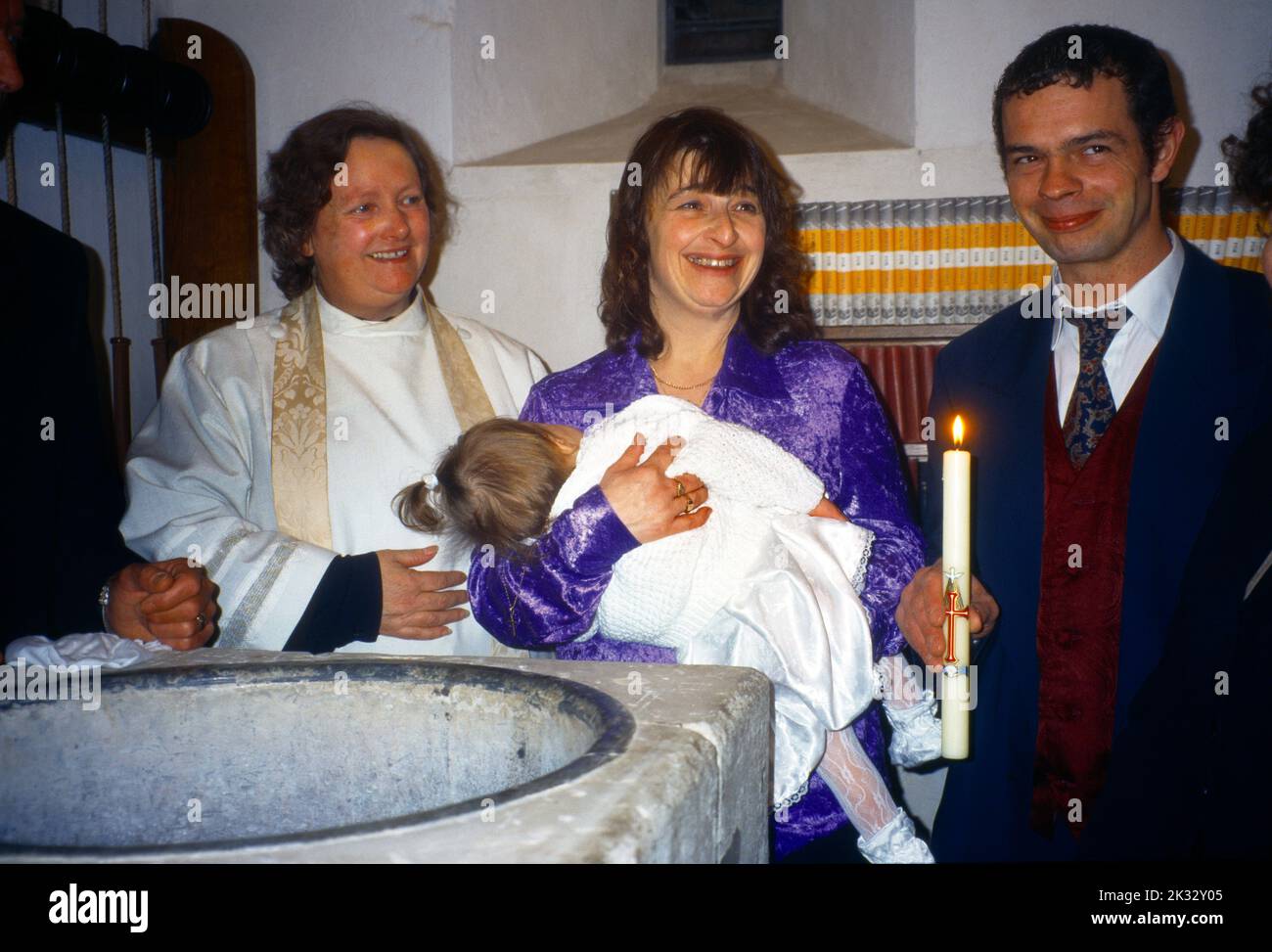 Christening Parents holding Daughter and Paschal Candle Chaldon Church Surrey Female Minister Stock Photo