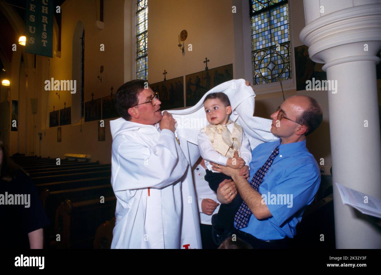 St Joseph's Church Roehampton Priest & Parent Wrap White Cloth Round Baby Stock Photo