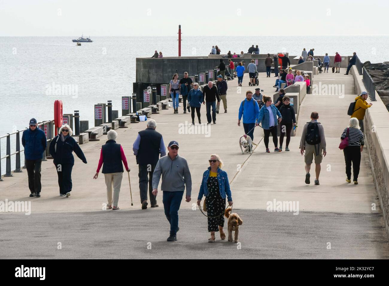 West Bay, Dorset, UK.  24th September 2022.  UK Weather.  The pier at the seaside resort of West Bay in Dorset is busy with visitors and locals enjoying the warm afternoon hazy autumn sunshine.  Picture Credit: Graham Hunt/Alamy Live News Stock Photo