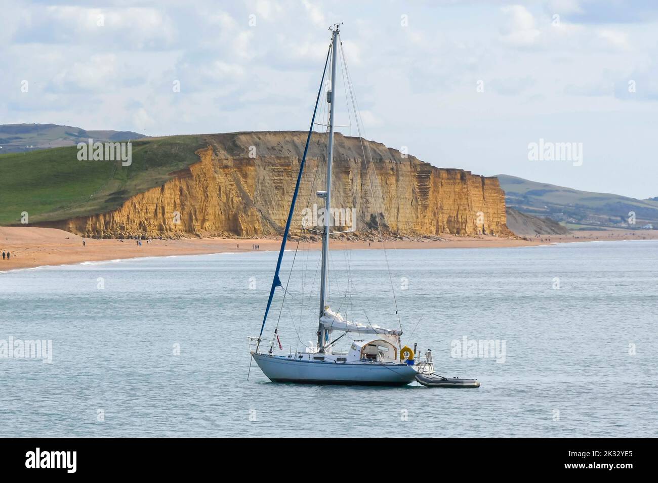 West Bay, Dorset, UK.  24th September 2022.  UK Weather.  A yacht anchored off the beach at the seaside resort of West Bay in Dorseton a warm afternoon with hazy autumn sunshine.  Picture Credit: Graham Hunt/Alamy Live News Stock Photo