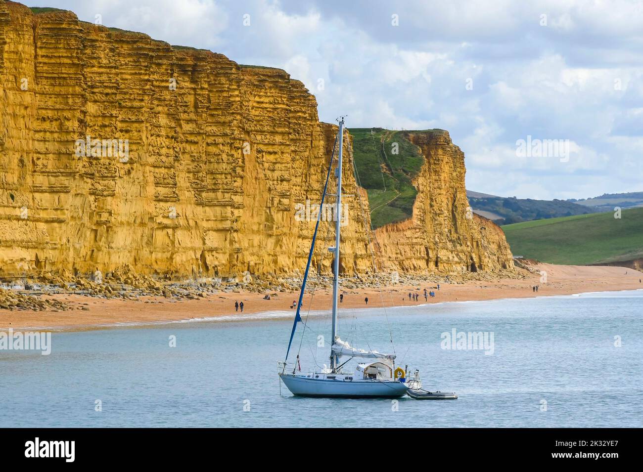 West Bay, Dorset, UK.  24th September 2022.  UK Weather.  A yacht anchored off the beach at the seaside resort of West Bay in Dorseton a warm afternoon with hazy autumn sunshine.  Picture Credit: Graham Hunt/Alamy Live News Stock Photo