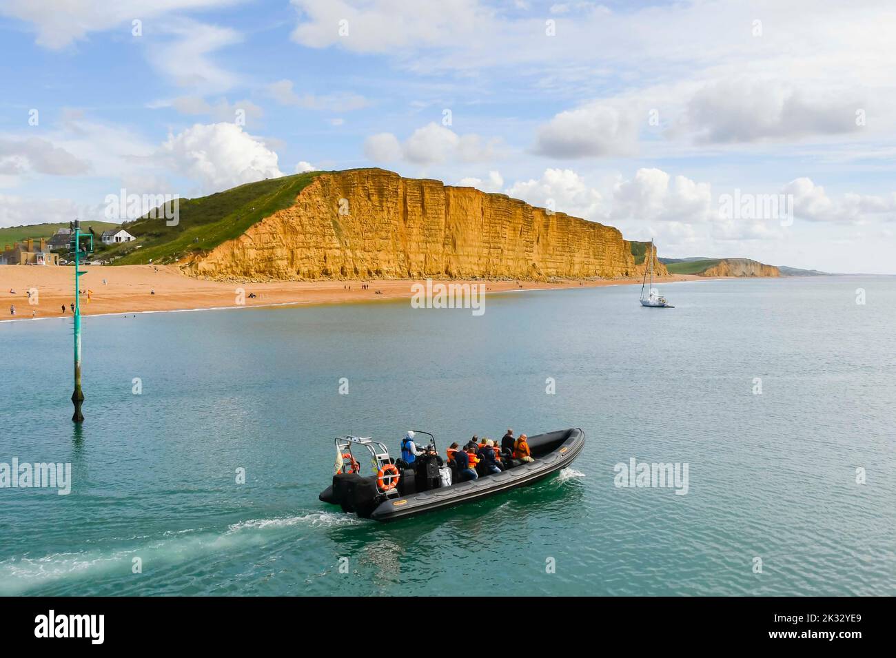 West Bay, Dorset, UK.  24th September 2022.  UK Weather.  A rib speedboat with visitors heads out on to the calm sea for a sightseeing trip at seaside resort of West Bay in Dorset on a warm afternoon with hazy autumn sunshine.  Picture Credit: Graham Hunt/Alamy Live News Stock Photo