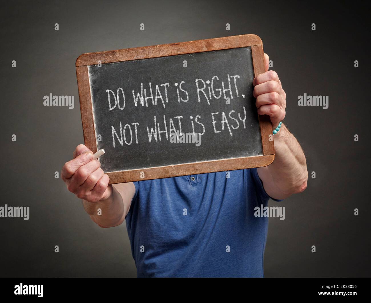 Do what is right, not what is easy - white chalk text on a slate blackboard held by male teacher, presenter or mentor, ethics concept Stock Photo