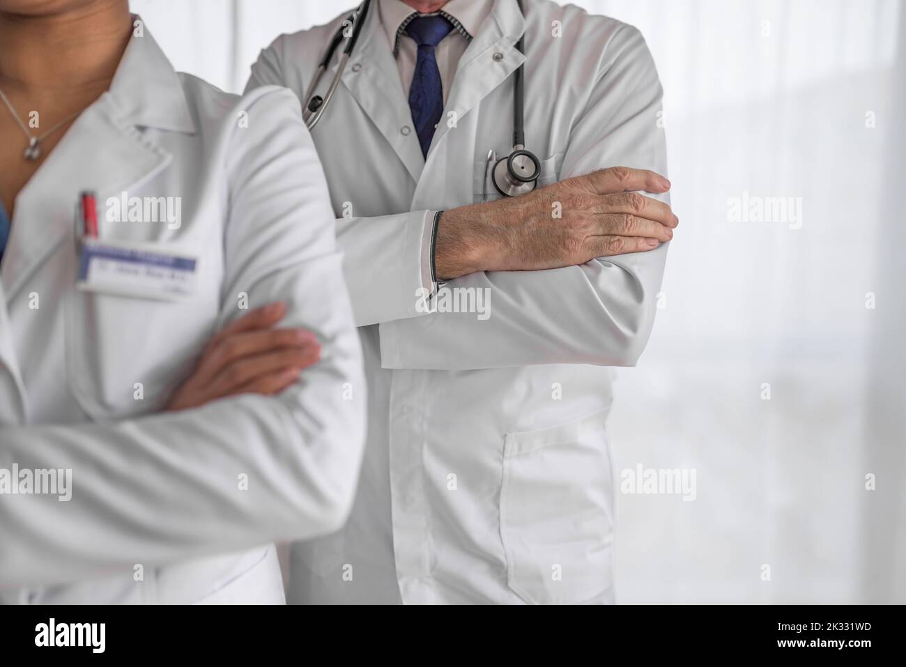 Picture of two hospital colleagues, standing cross-armed, preparing for their shift. Stock Photo