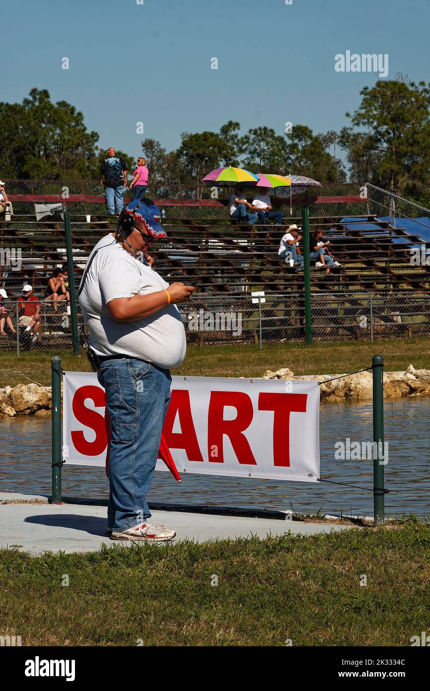 man with very large belly, protruding over jeans, side view, race starter, headphones, swamp buggy races, Florida Sports Park, Naples, FL Stock Photo