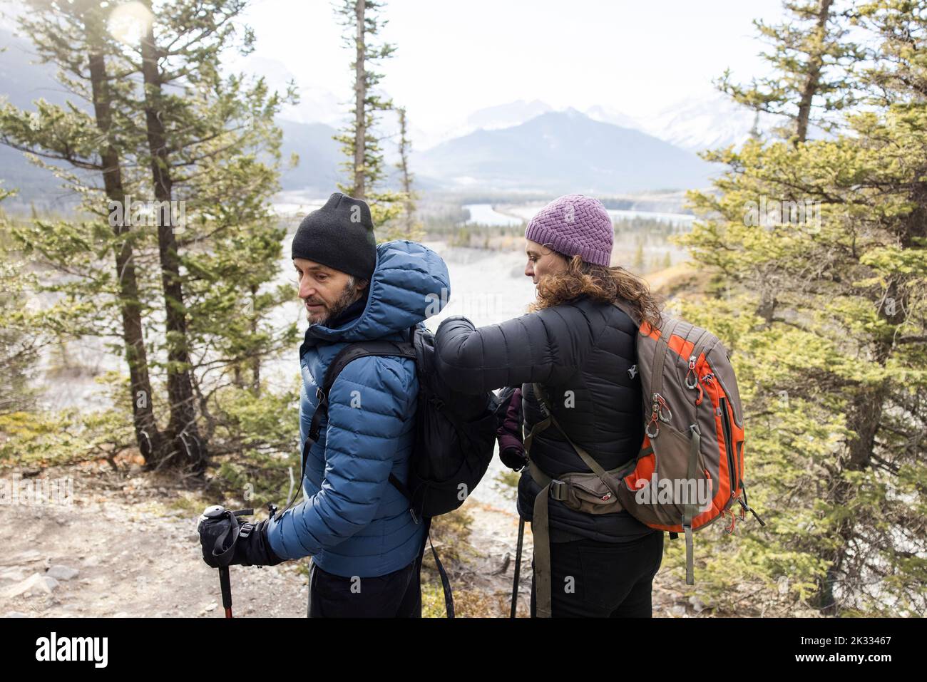 Woman fastening husbands backpack on forest hike Stock Photo