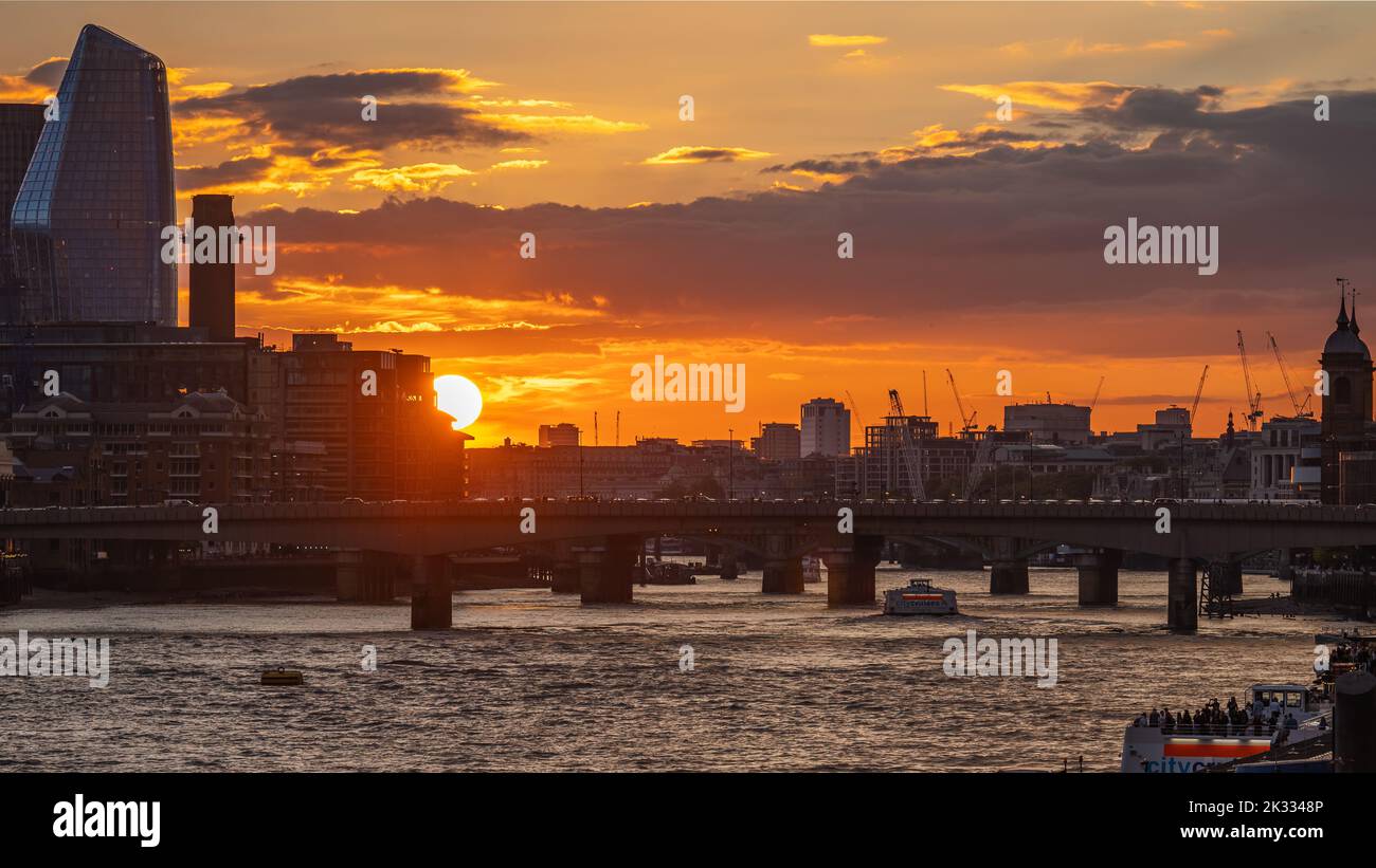 London Bridge Sunset: Sunset over London Bridge, with an orange sky, silhouetted buildings and river taxis on the Thames. Shot from Tower Bridge. Stock Photo