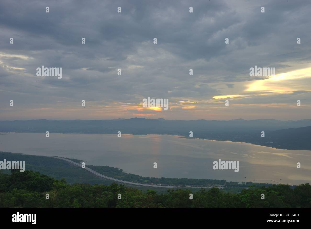 A cloudy sky with a scenic sunset over a lake and forests Stock Photo ...