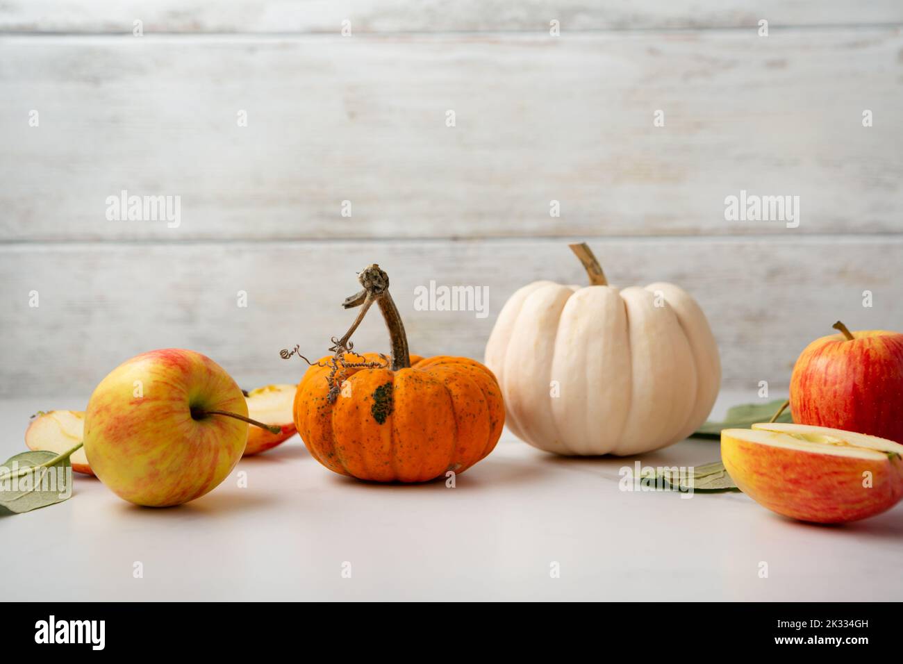 Small pumpkins and apples on light surface copy space food Stock Photo