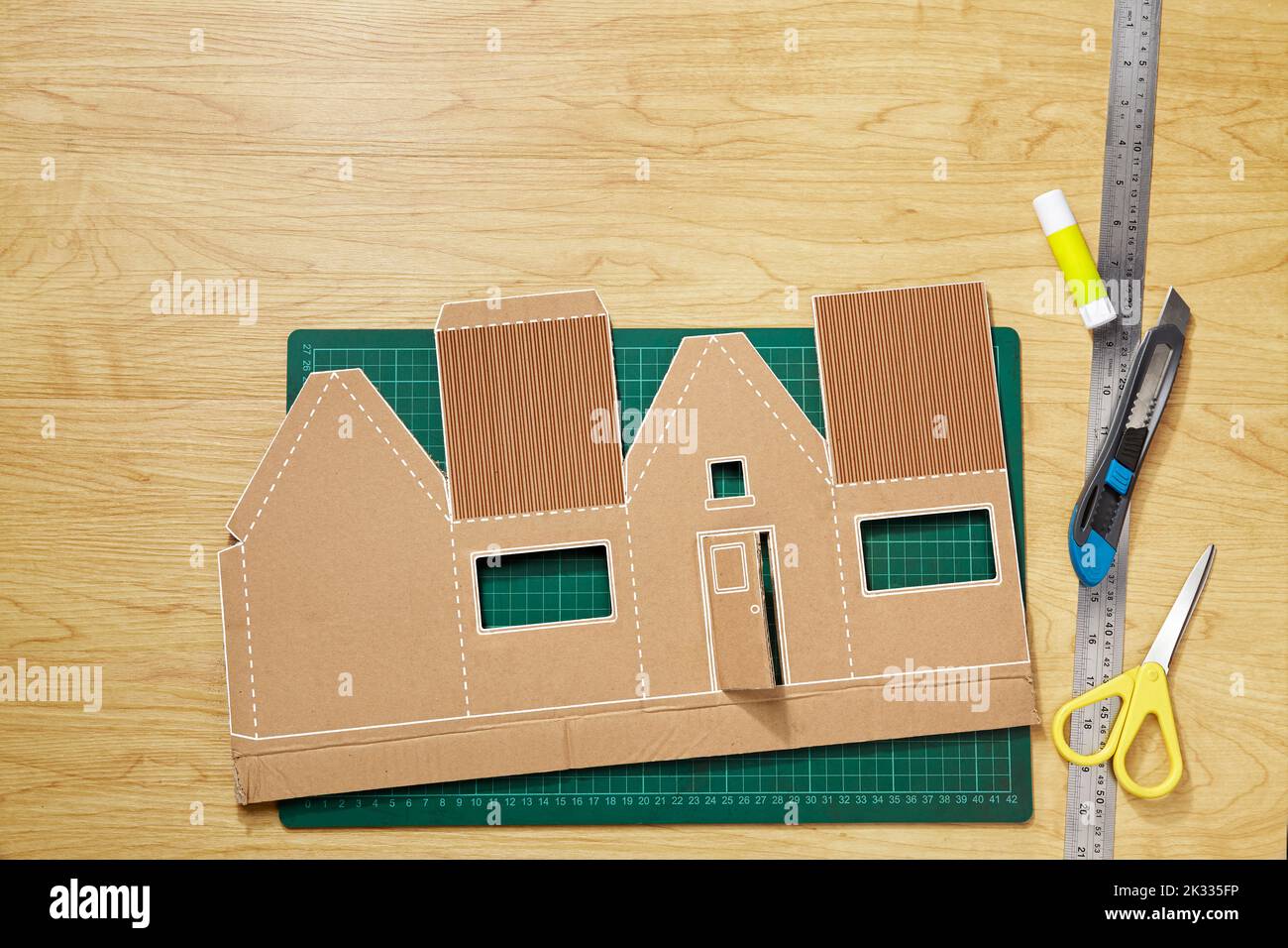 A craft pattern from cardboard that has been cut, ready to be shaped and glued into a miniature house Stock Photo