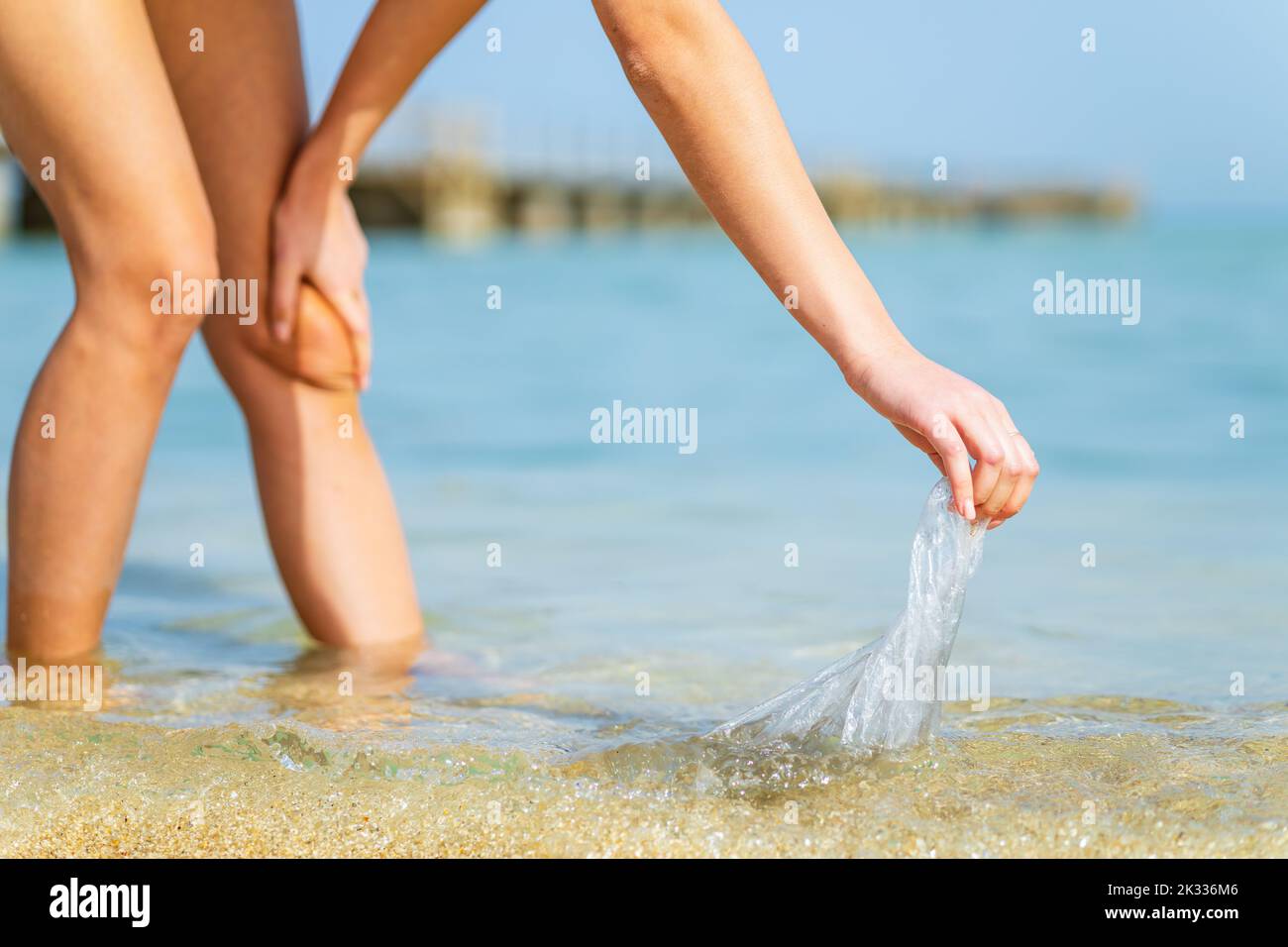 A female volunteer picks up plastic plastic on the ocean shore Stock