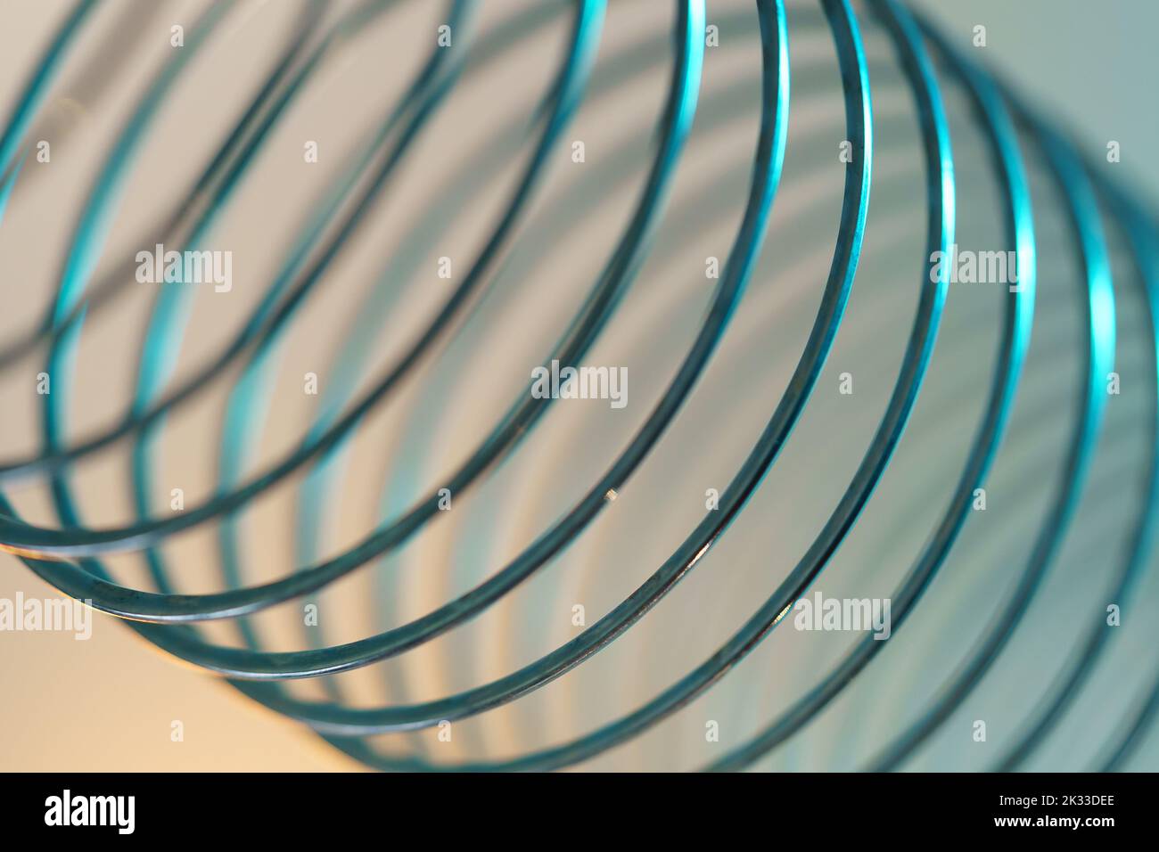 Closeup of coiled metal spring with sufficiently high strength and elastic properties in neon light Stock Photo