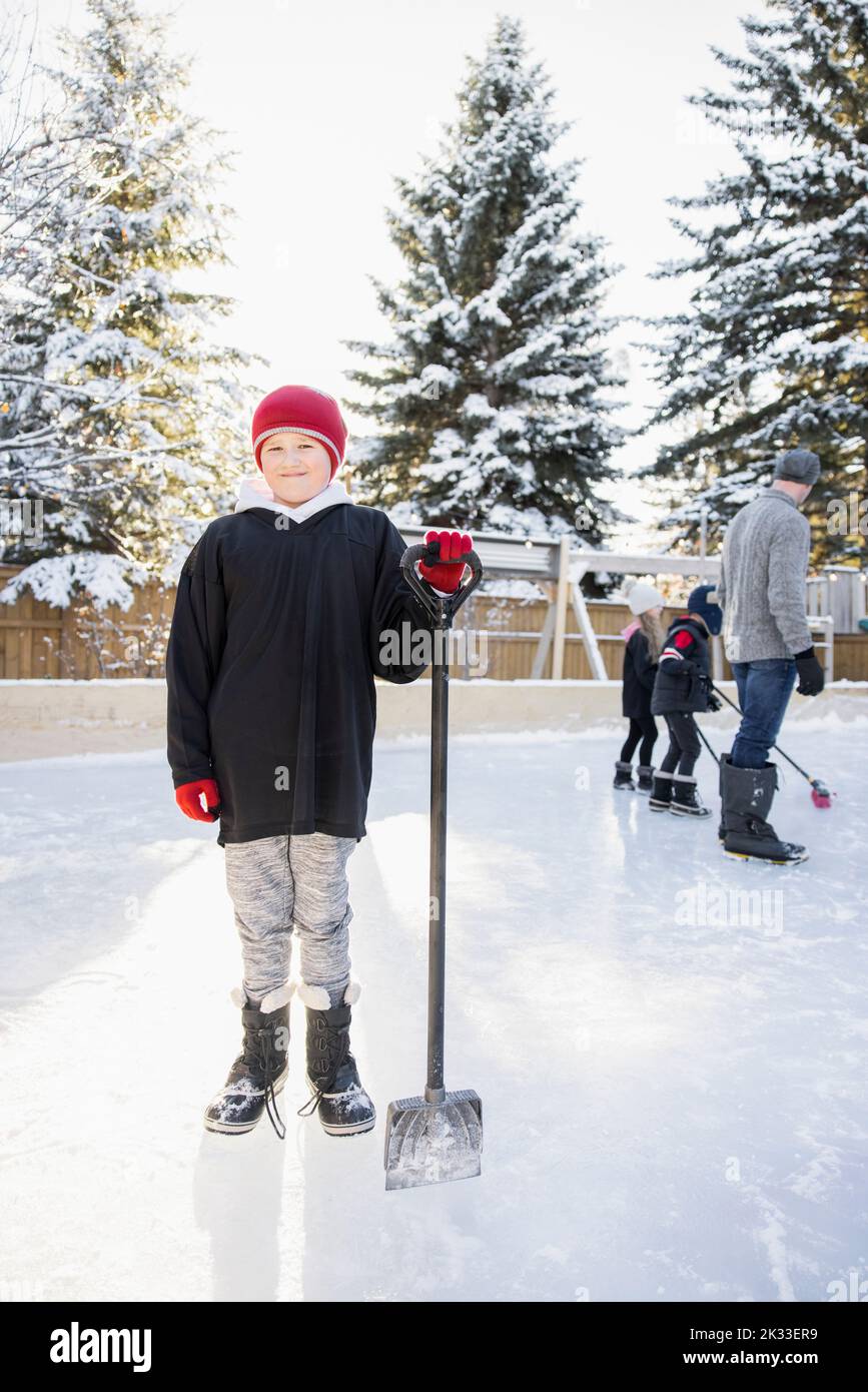 Portrait happy boy with shovel on backyard ice rink Stock Photo Alamy