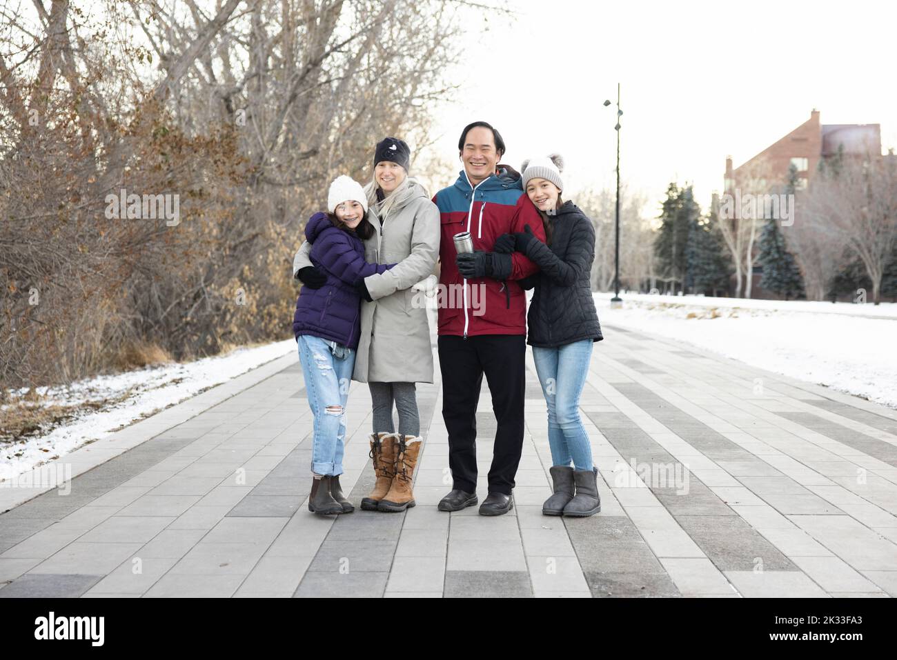 Portrait happy family in winter coats on path in city park Stock Photo