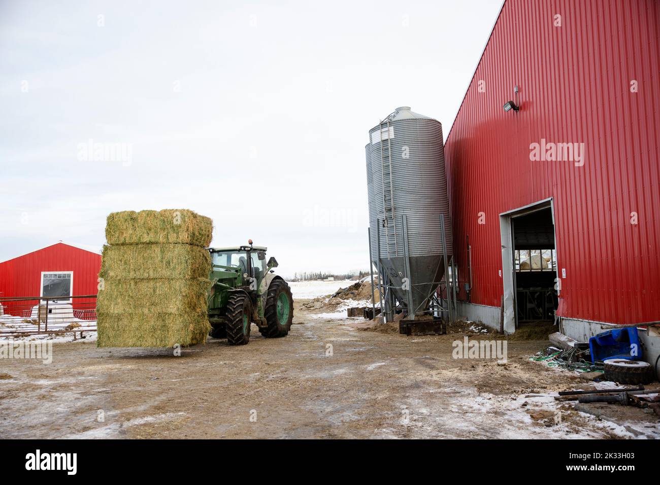 Tractor carrying haystack on farmyard Stock Photo