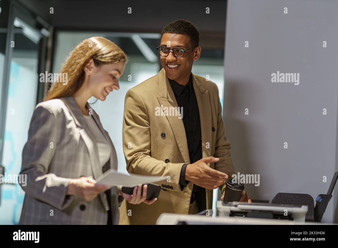 Two business people are talking while scanning documents on a scanner Stock Photo
