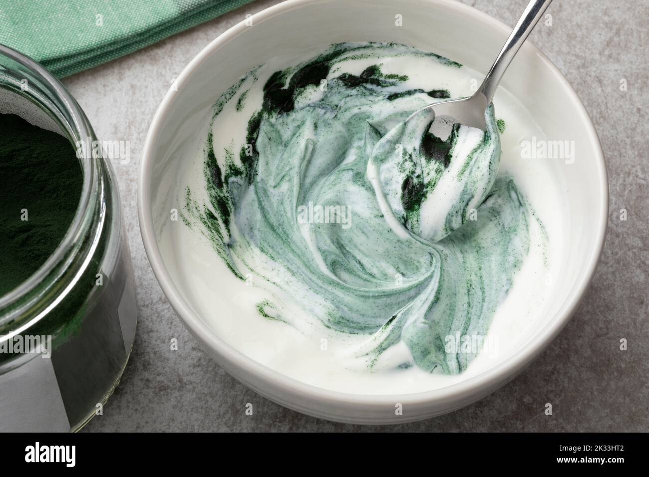 Bowl of yogurt with healthy green spirulina powder close up for breakfast Stock Photo