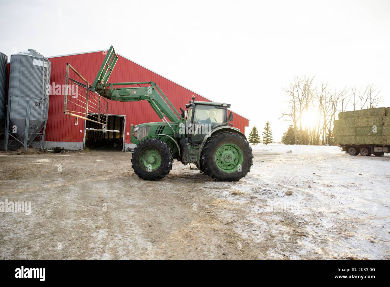 Farmer driving tractor on farmyard Stock Photo