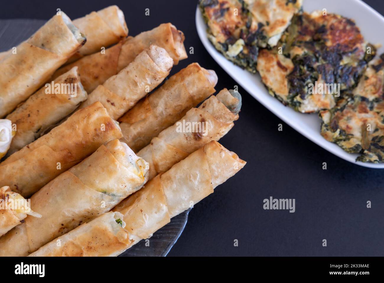 Turkish Cigar Shaped Rolls. Traditional Borek, Burek, cooked, grilled fresh spring rolls food on black background. Copy Space, Top View. Stock Photo