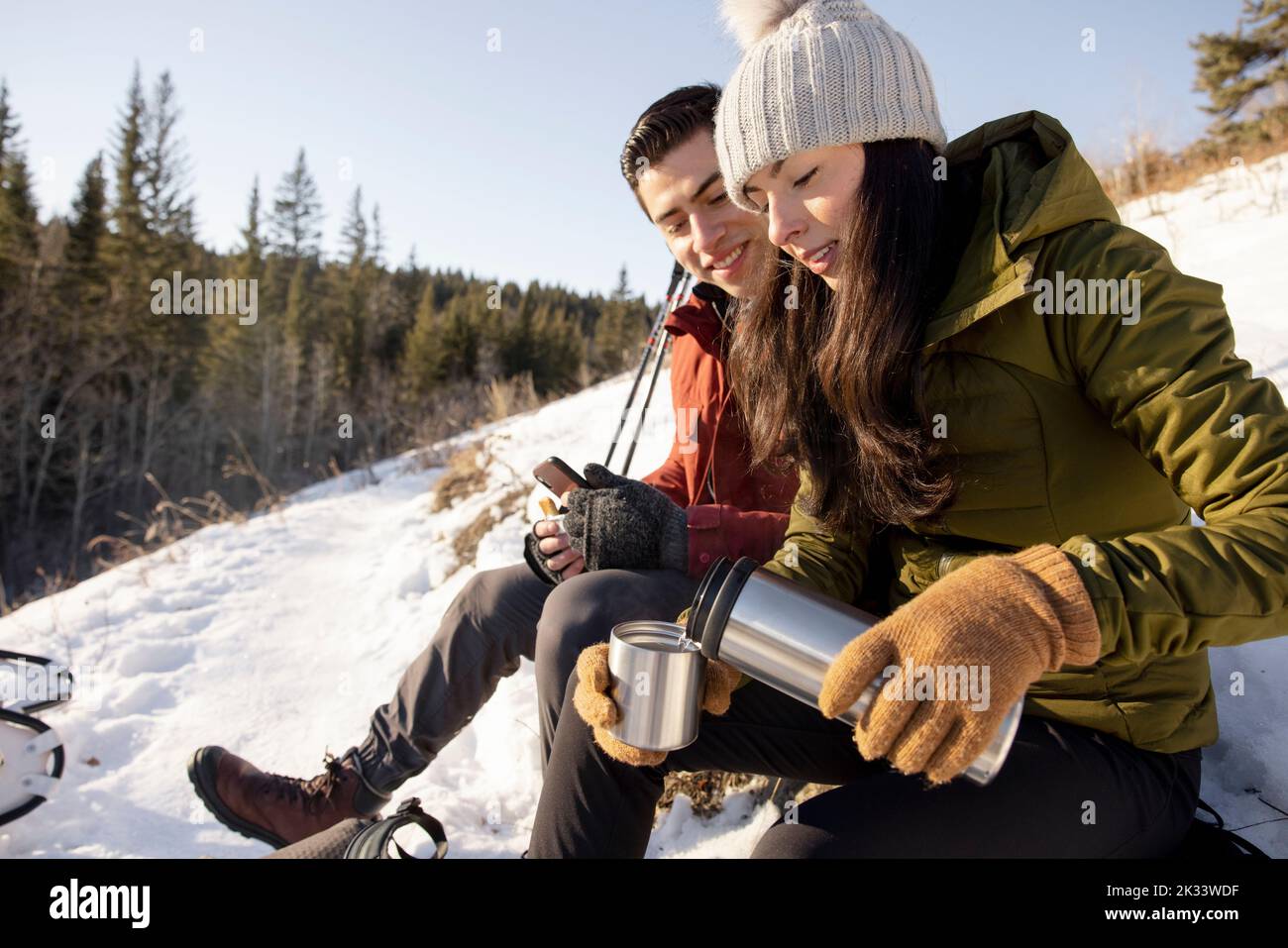 Couple stopping for drink on snowy hike Stock Photo