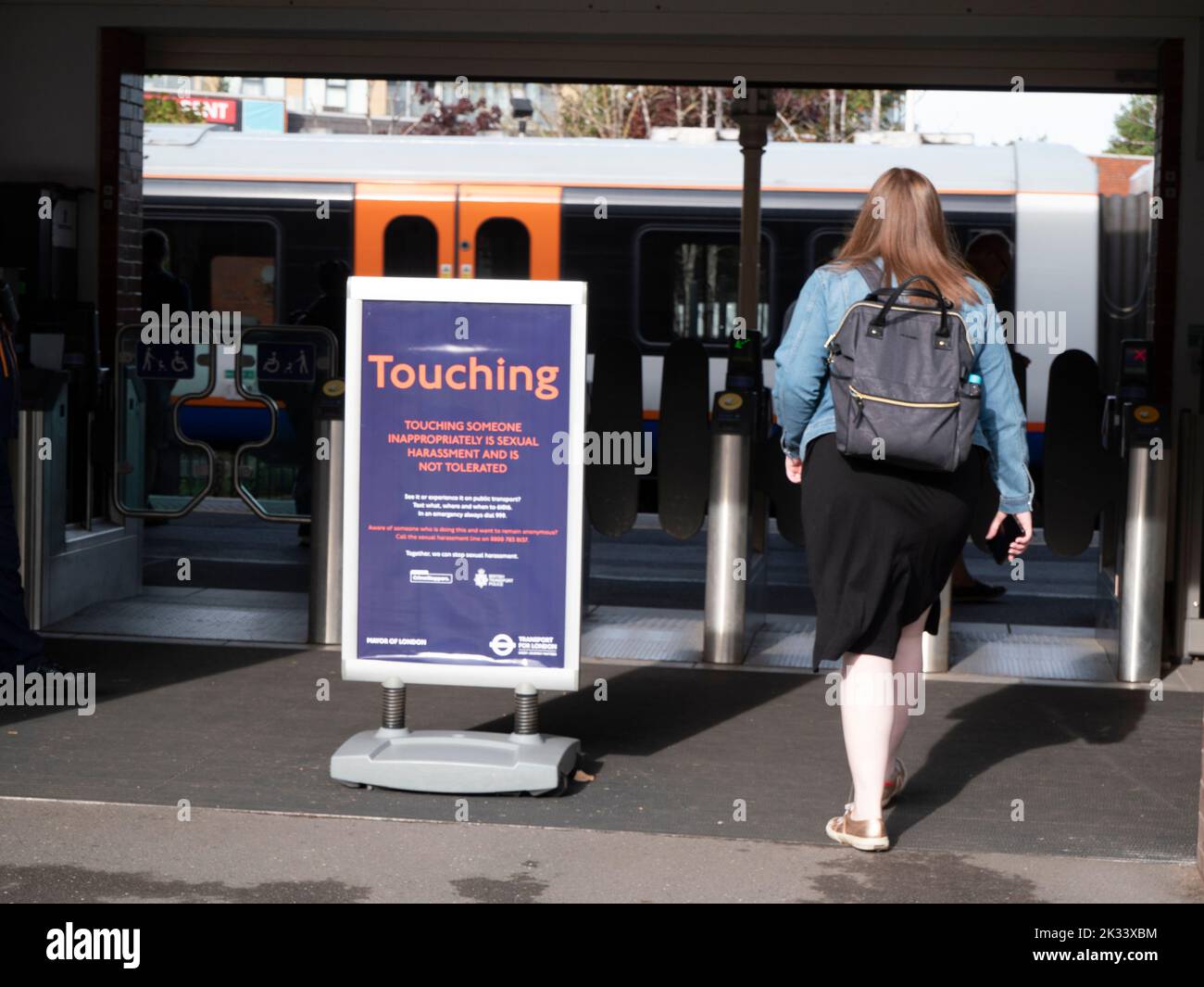 transport for London Overground railway entrance to platform barriers with sign Touching someone inappropriately is sexual harrassment and is not tolerated Stock Photo