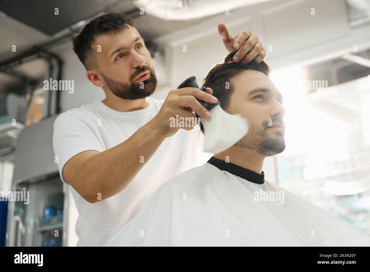 Cheerful guy enjoying top quality service at hair salon Stock Photo