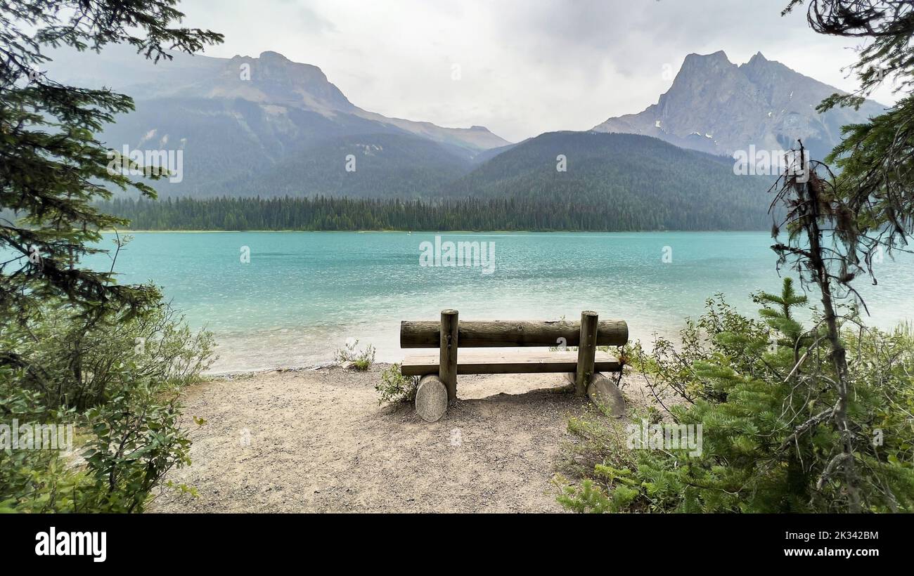 A bench on the shore of Emerald Lake with Wapta Mountain, and Mount Burgess. Yoho National Park. Stock Photo