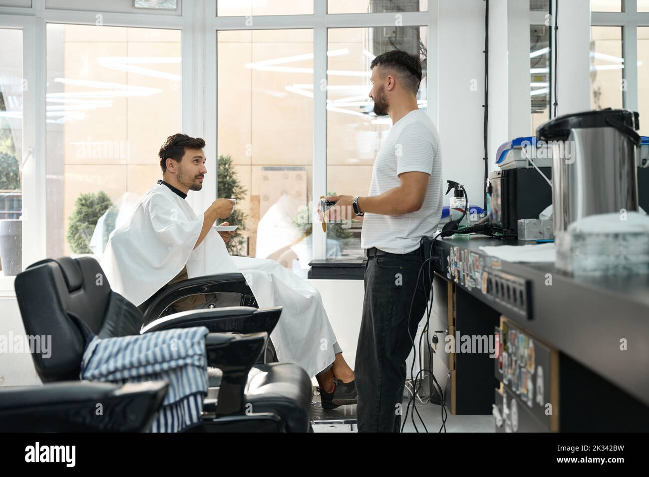 Brunette guy looking pleased with quality service at hair salon Stock Photo