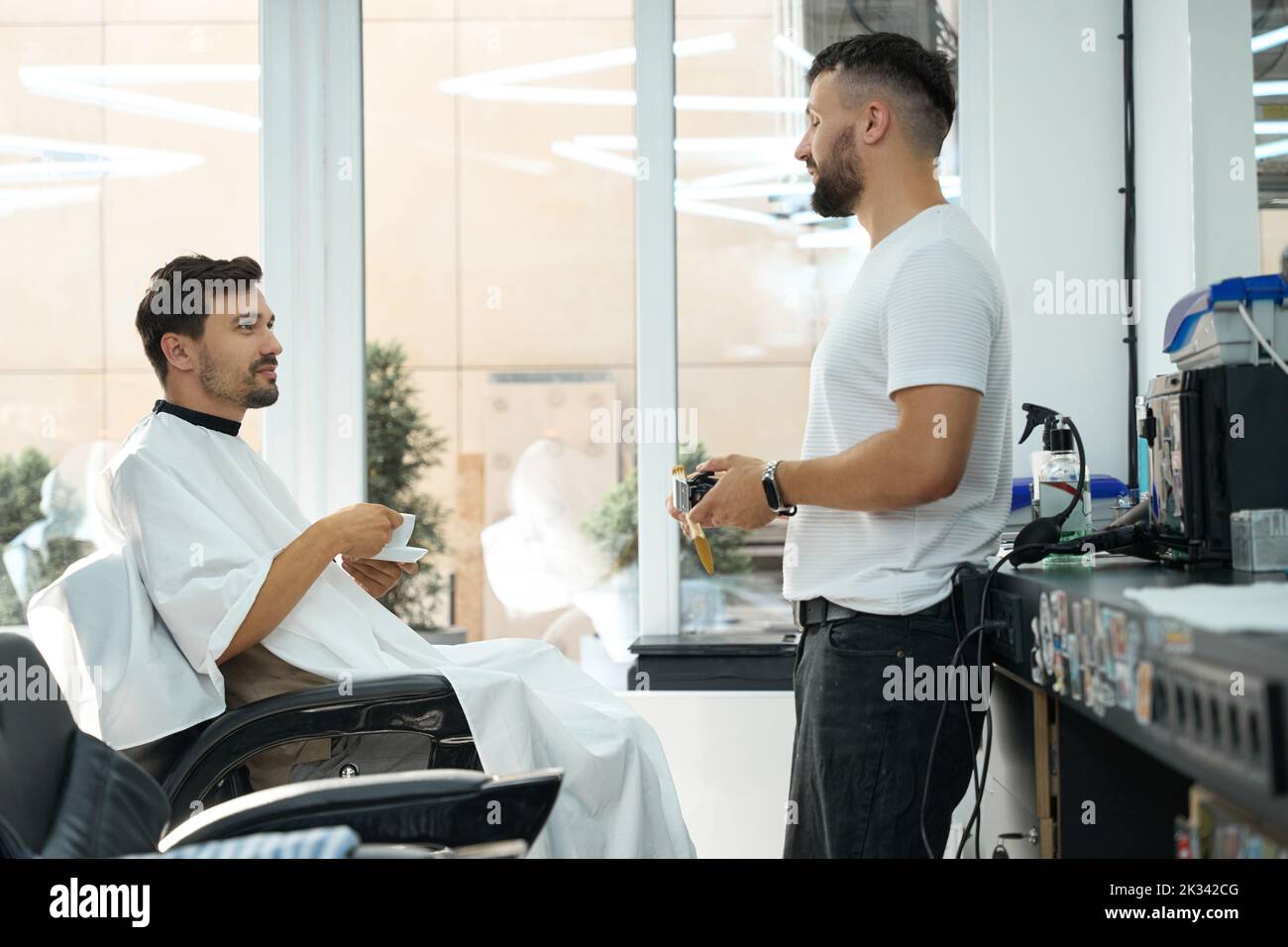 Contented handsome man enjoying coffee and service in hair salon Stock Photo