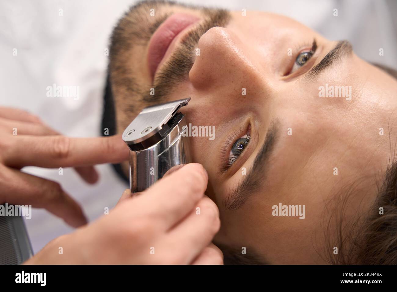 Serious man not moving while barber trimming his moustache Stock Photo