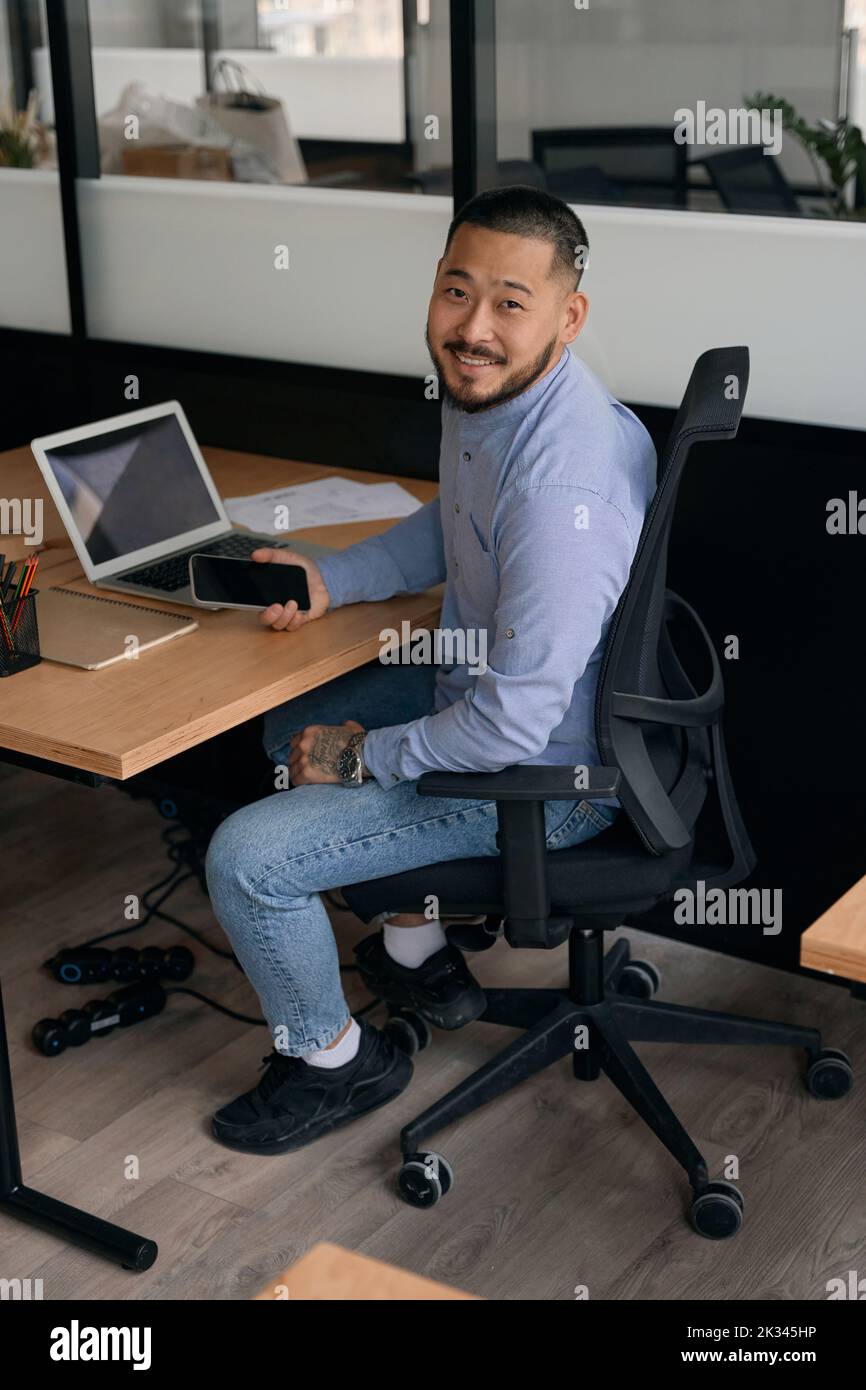 Joyous company employee posing for camera at office desk Stock Photo