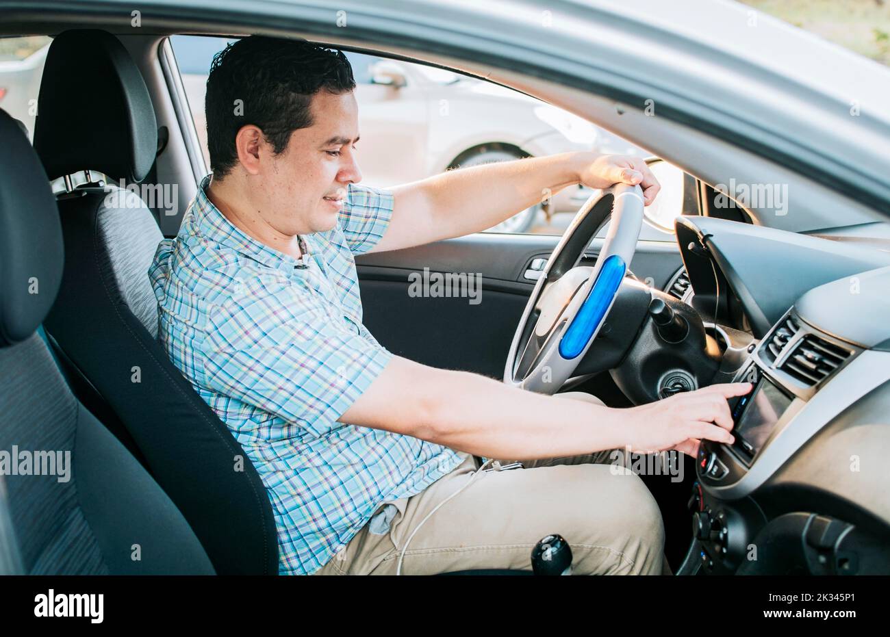 Driver man changing the radio station. Smiling driver tuning into the radio station. Distracted driver concept tuning the radio. Driving people Stock Photo